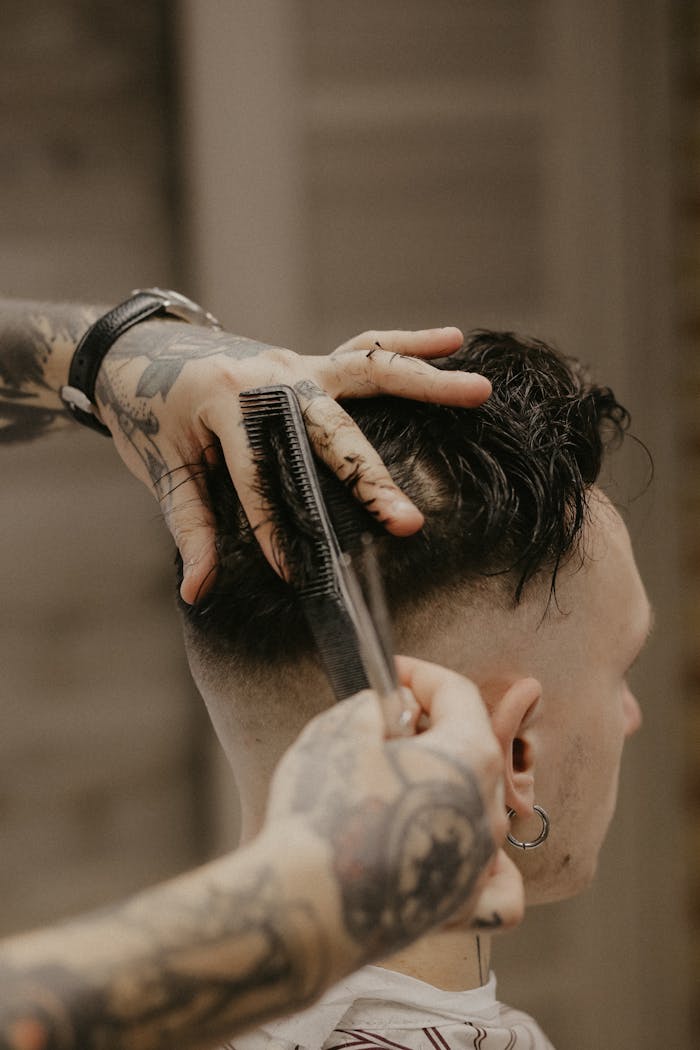 Home A barber with tattoos trims a man
