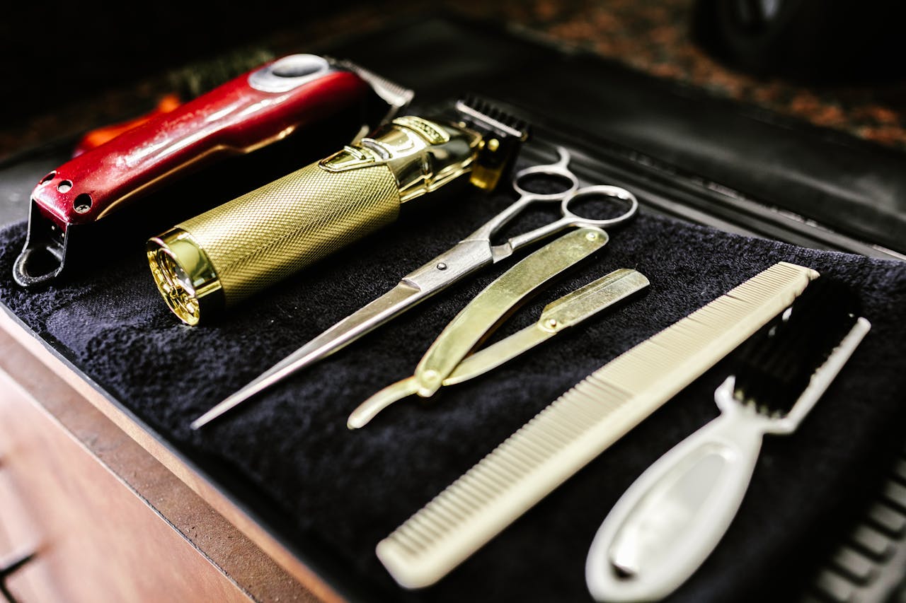 Home A collection of essential barbershop tools including trimmers, scissors, and razors neatly arranged.